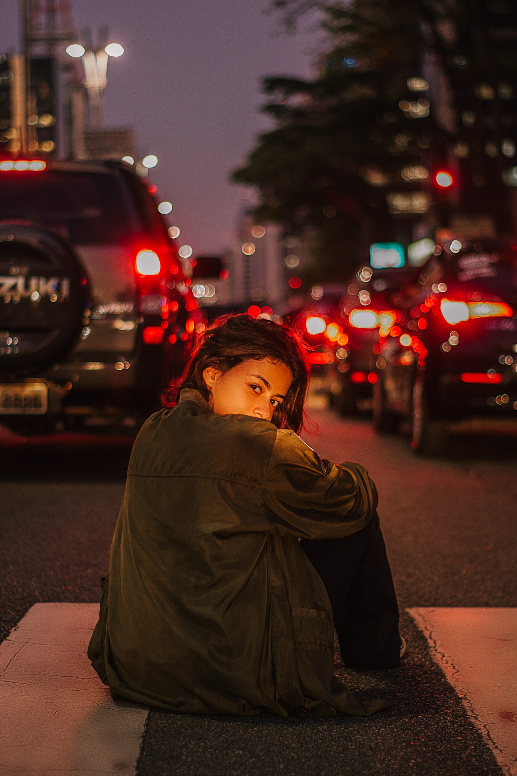 woman-sitting-on-road-during-night-time-1970482